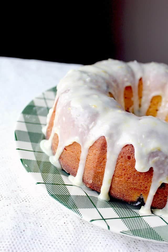 Close up of Greek Yogurt Blueberry Lemon Bundt with Lemon Icing Glaze placed on a green checkered plate