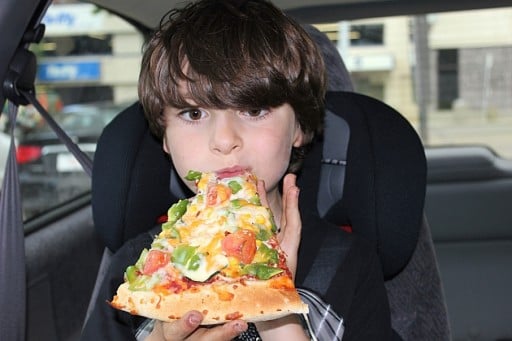 a kid enjoying a large size of pizza