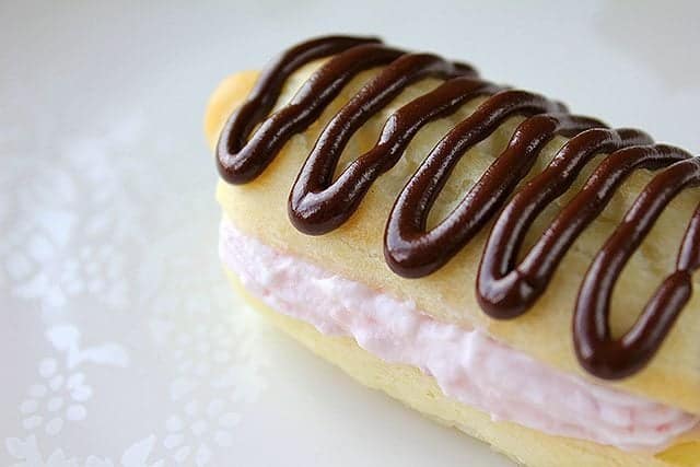 Strawberry Cream Filled Chocolate Drizzled Eclair in a white background