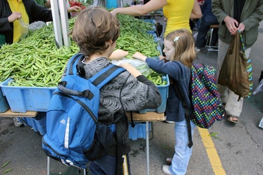 kids with backpacks picking some peas