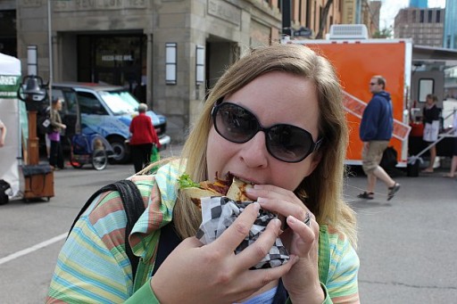 a woman in sun glasses taking a bite on her sandwich