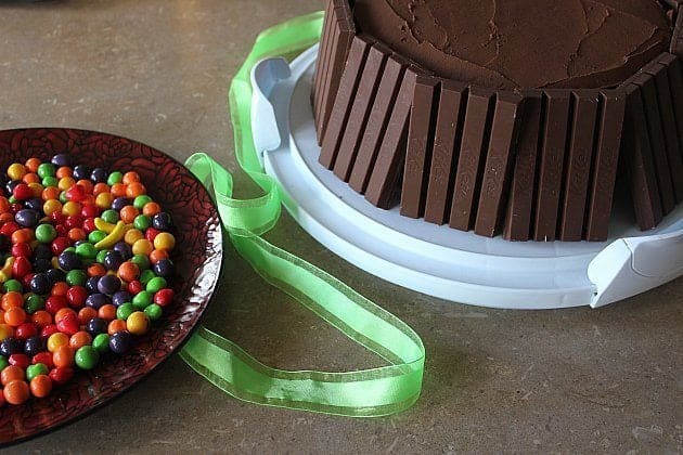 Vertically lined up KitKat bars on the outside of the cake. Wonka Candy are ready in a red plate