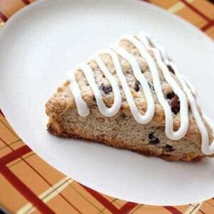 a slice of Simple Carrot Cake Scones in a white plate, drizzled with tangy cream cheese icing