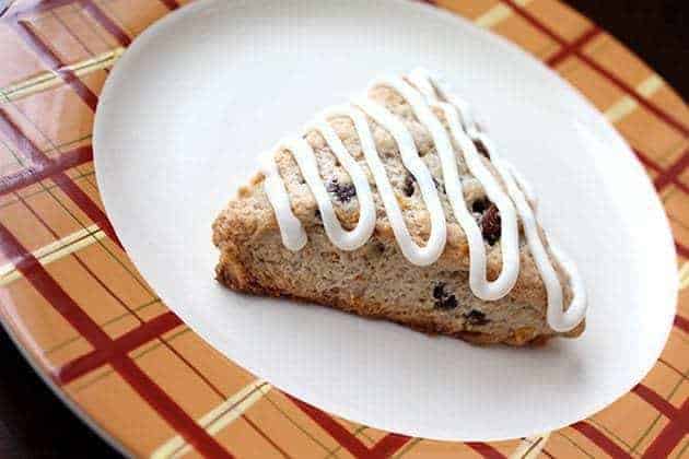 a slice of Simple Carrot Cake Scones in a white plate, drizzled with tangy cream cheese icing