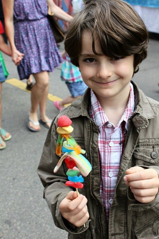 little boy smiling while holding his stick of candies