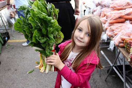 little girl holding a bundle of green leafy vegetable