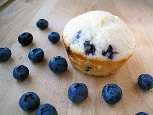 piece of Lemon Blueberry Muffin and some fresh blueberries around it