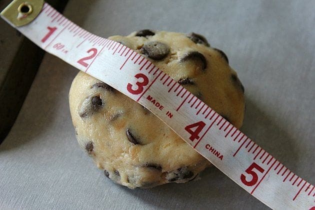 measuring the chocolate chip cookie dough using a tape measure