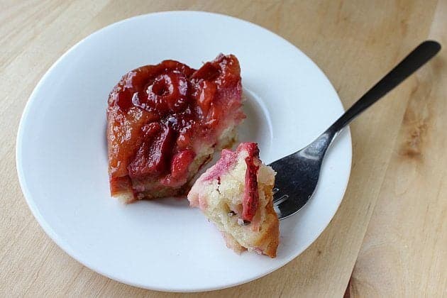A slice of Strawberry Rhubarb Upside Down Cake in a white dessert plate