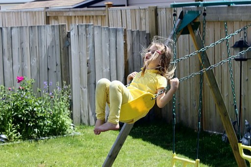 little girl wearing yellow enjoying the swing