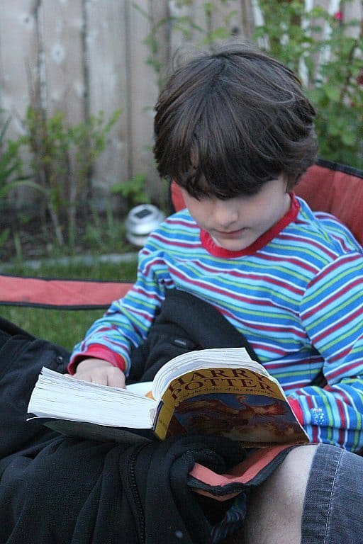 a kid reading book while sitting on a camping chair