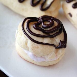 Eclair filled with whipped cream with crunchy chocolate drizzles on top