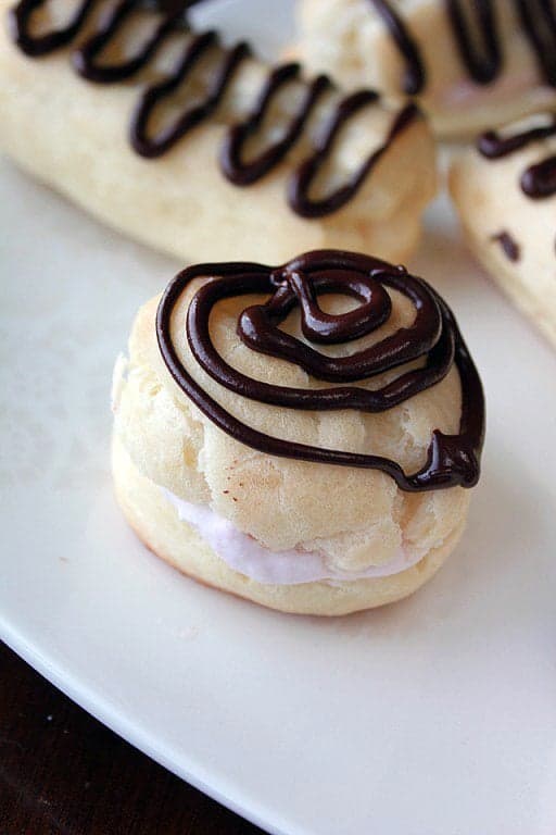 Eclair filled with whipped cream with crunchy chocolate drizzles on top