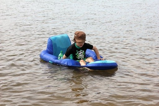 a boy in a blue floating chair in the beach