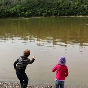 two little kids throwing stones to the river