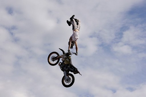 doing a handstand on the handlebars of the motorbike while on the air
