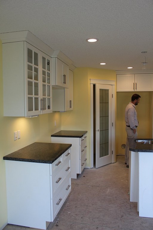 the kitchen area with white cabinets and granite table top