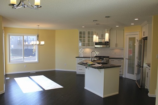 kitchen with white cabinetry and some glass fronts, pendant lighting and hardwood flooring