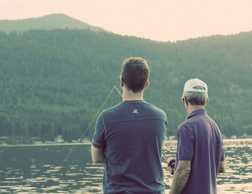 two men facing the lake waiting to catch a fish