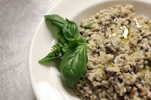 Wild Mushroom Risotto in a white plate, garnish with basil leaves
