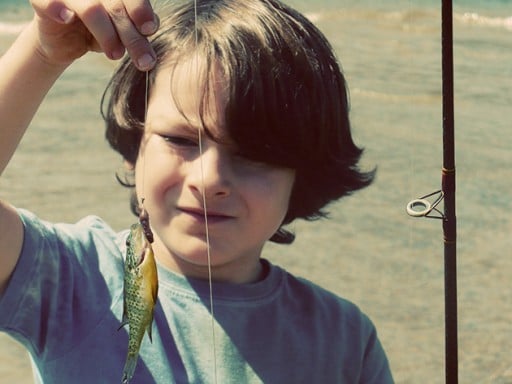 close up of a boy and the fish that he caught in the string