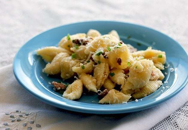 Baked Cheesy Bacon & Chanterelle Pasta in a blue plate over white cloth