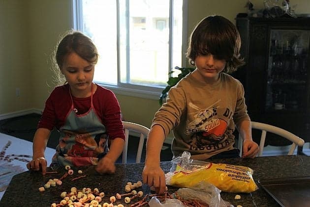 children doing the mini Pretzel & Marshmallow Bones by having the marshmallows stuck on the ends of pretzels, dipping in white chocolate and ending up looking like bones.