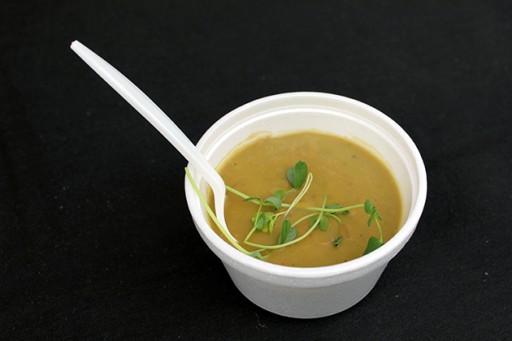 a cup of delish soup with some leaves and a spoon in it