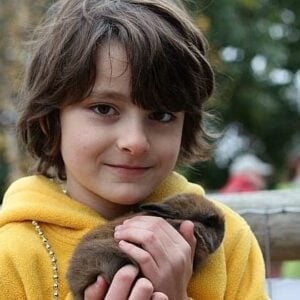 close up of a boy holding a brown rabbit