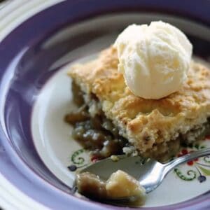 close up of a slice of PEAR COBBLER topped with vanilla ice cream on a blue designed plate