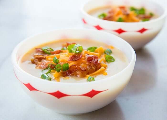 Two Bowls of Cheesy Bacon Potato Soup Served with Tex Mex Cheese, chopped green onions and extra bacon on top