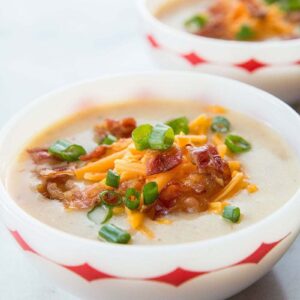 Two Bowls of Cheesy Bacon Potato Soup Served with Tex Mex Cheese, chopped green onions and extra bacon on top