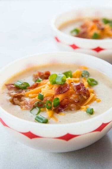 Two Bowls of Cheesy Bacon Potato Soup Served with Tex Mex Cheese, chopped green onions and extra bacon on top