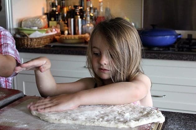 little girl flattening the dough