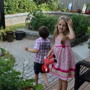 little girl in pink dress bare footed holding her pink stuff toy