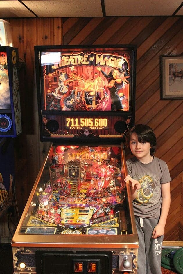 little boy standing beside the pinball machine