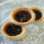 close up 3 pieces Butter Tarts with raisins on a white floral tablecloth background