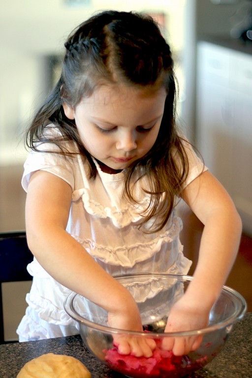 little girl wearing white busy with the mixing bowl