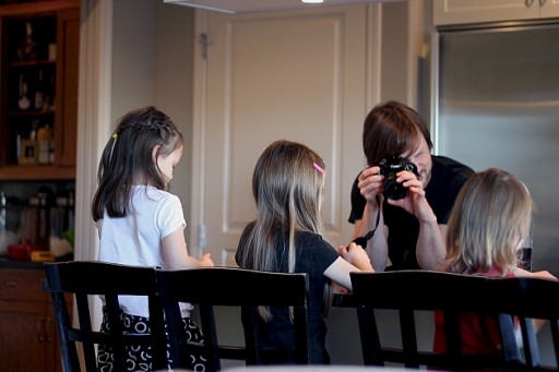 three little girls in the chair busy with their things in front of the camera man