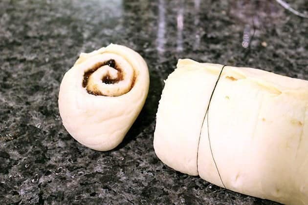 cutting the rolled up Rum Glazed Mincemeat Cinnamon dough