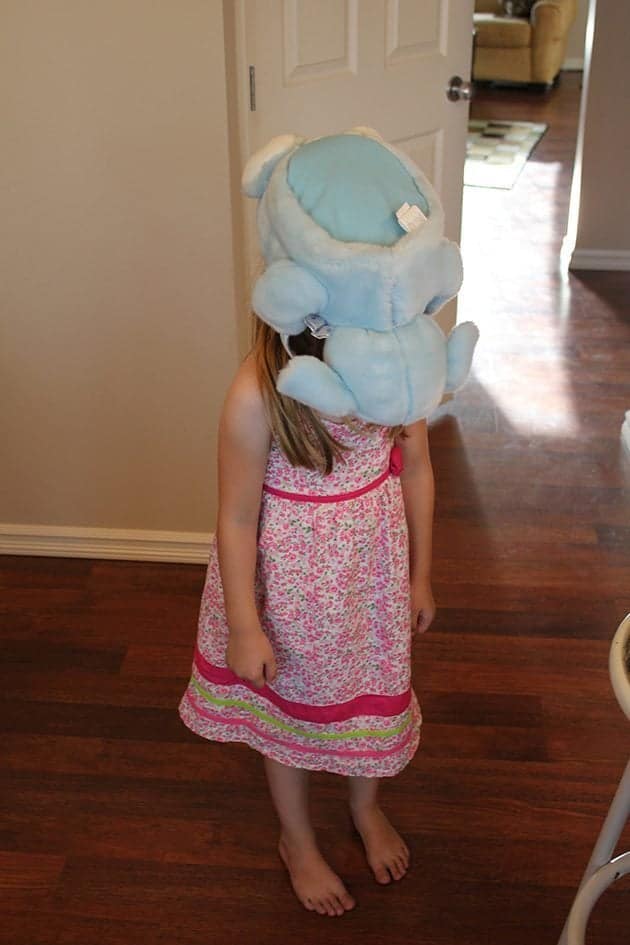 little girl with a stuff toy on her head and face