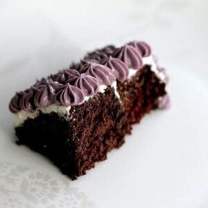 Gluten Free Chocolate Cake topped with violet vegan icing on white background