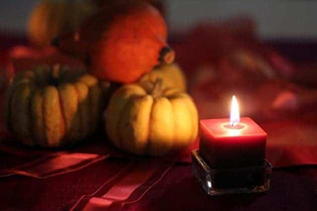 close up of pumpkin decors and square lighted candle on the table