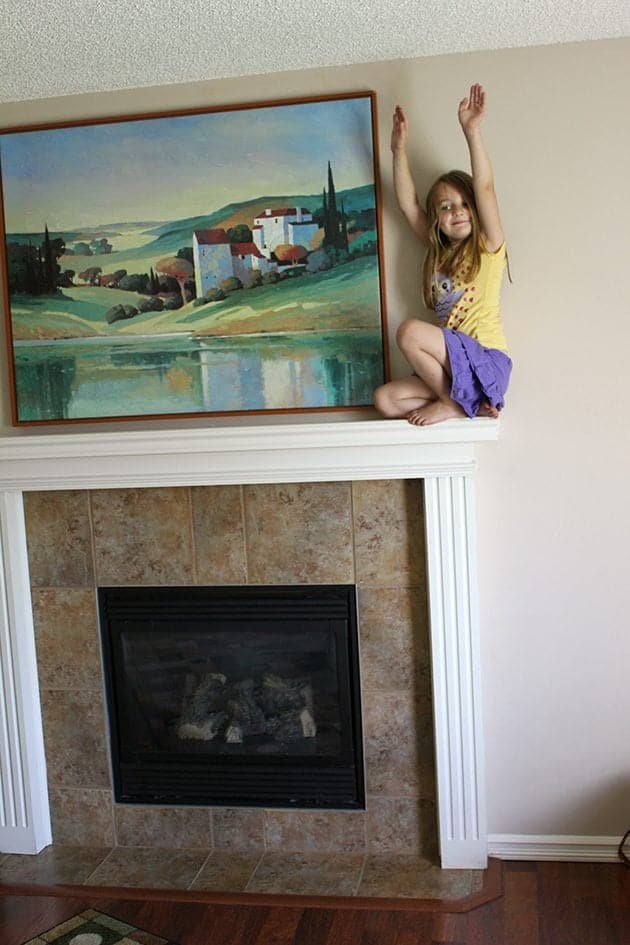 little girl on top of the fireplace near the wall painting