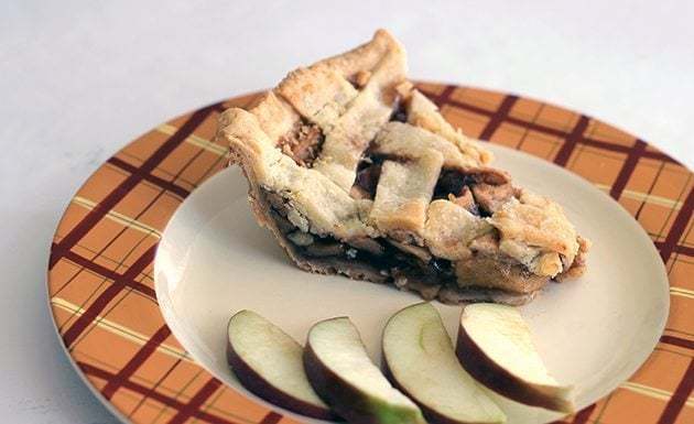 Slice of Homemade Sweet Apple Pie with slices of apple in an orange printed plate