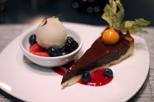 white plate with Callebeaut chocolate mascarpone tarte, champagne sorbet topping and honey marinated berries