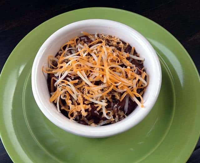 top down shot of six Ingredient Black Bean Soup in a white soup bowl on a green plate