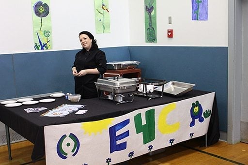 set up of E4C's table with a woman wearing all black standing beside it