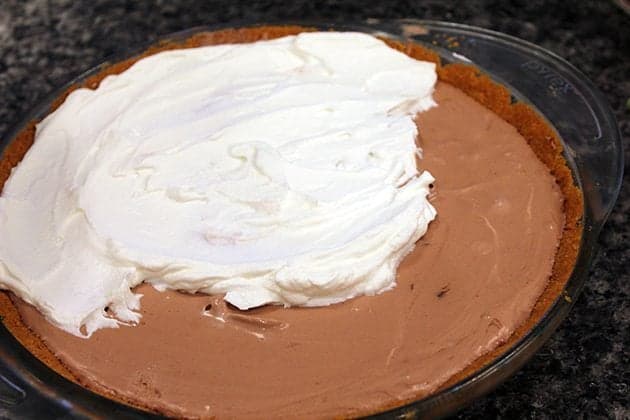 adding more whipped cream on top of Mousse Pie