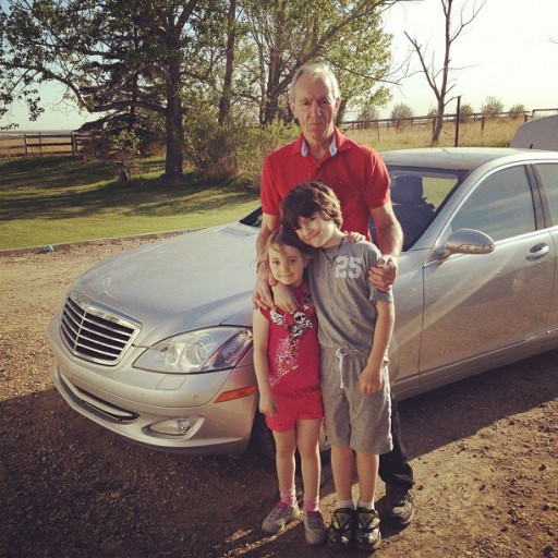 grandfather and two kids with a car in their background